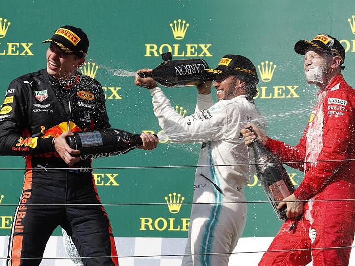 Champagnerdusche: Sieger Lewis Hamilton (M) mit Max Verstappen (l) und Sebastian Vettel auf dem Podium in Budapest.