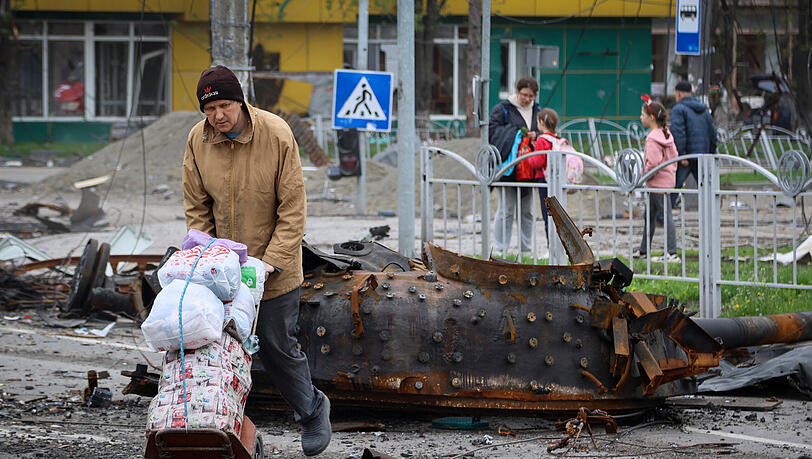 Mariupol: Anwohner neben einem beschädigten Militärfahrzeug. Mariupol: Anwohner neben einem beschädigten Militärfahrzeug.