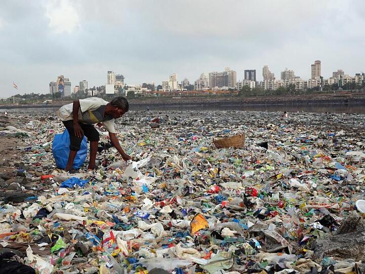 Ein Mann sammelt Plastik an der von Müll übersäten Küste des Arabisches Meeres in Mumbai.