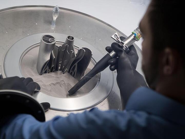 Ein Mitarbeiter arbeitet an einem im 3D Druck gefertigten Bauteil. Foto: Marijan Murat/dpa