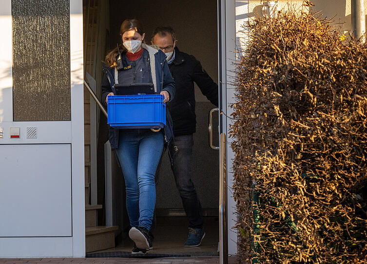 Polizeibeamte verlassen in den frühen Morgenstunden, während einer bayernweiten Polizeiaktion gegen Beleidigungen von Politikern, das Haus einer verdächtigen Person.