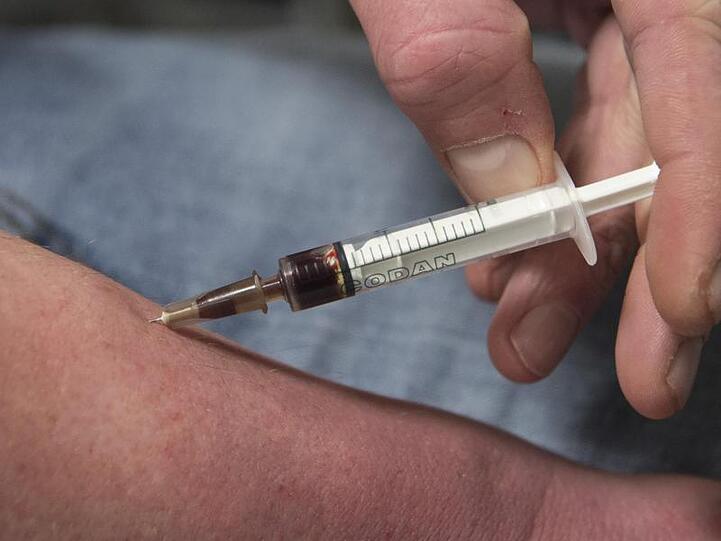 Ein Drogensüchtiger spritzt sich in einem Druckraum einen Schuss Heroin in den Unterarm.