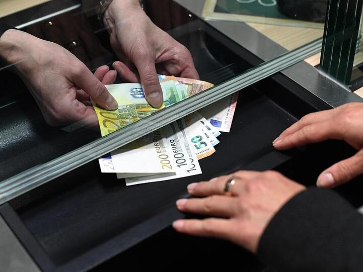Eine Frau lässt sich in einer Bankfiliale am Schalter Bargeld auszahlen.