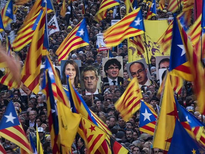 Demonstranten tragen bei der Massenkundgebung in Barcelona Fahnen und Bilder ehemaliger katalanischer Regierungmitglieder.