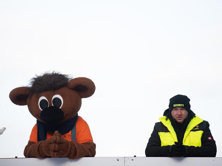 WM-Maskottchen Bobby und ein Sicherheitsmann beobachten die Zieleinfahrt in Altenberg.