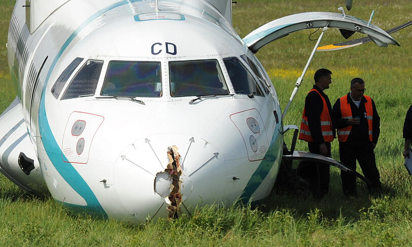 Mitarbeiter des Flughafens in München betrachten die Maschine der italienischen Fluggesellschaft, die am Donnerstag auf dem Münchner Flughafen notlanden musste. Das Flugzeug mit 62 Menschen an Bord hatte kurz nach dem Start in Richtung Venedig umdrehen müssen, weil sich Rauch in der Kabine entwickelt hatte. Bei der Landung wurden fünf Personen leicht verletzt, die Maschine kam neben der Landebahn zum Stehen.