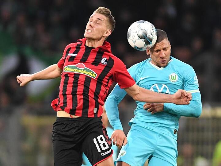Freiburgs Nils Petersen (l) kämpft mit Wolfsburgs Jeffrey Bruma (r) um den Ball.