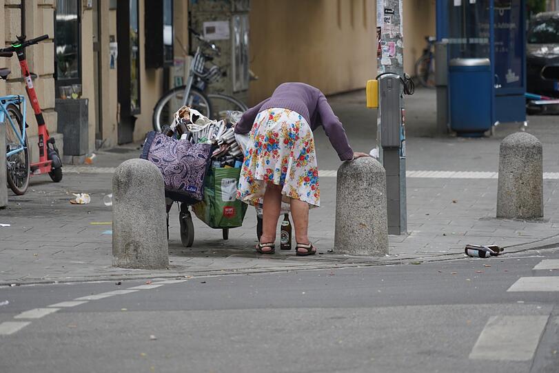 Eine Frau sammelt weggeworfene Pfandflaschen im Univiertel.