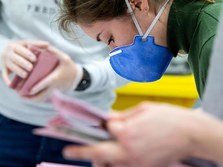 Eine Wahlhelferin trägt Schutzmaske, während sie die Auszählung der Briefwahl vorbereitet. Foto: Sven Hoppe/dpa