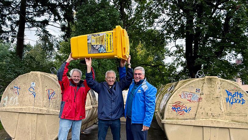 Von links.: Andreas Ellmaier, Ulrich Grasberger und Walter Worbs vom Verein Müllwende feiern die Gelbe Tonne als Teilerfolg. Doch sie finden das Müllsystem Münchens immer noch ineffizient. Über die Gelbe Tonne jubeln sie und haben bereits eine gekauft, zu Foto- und eben Jubelzwecken. Im Bild ist eine 80 Liter große Gelbe Tonne. Laut Grasberger kostet sie 49 Euro.