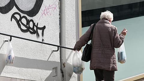 Die Pandemie verschärft die soziale Ungleichheit - manch einer ist auf die Hilfe von Fremden angewiesen, wie hier eine Frau an einem Gabengeländer.