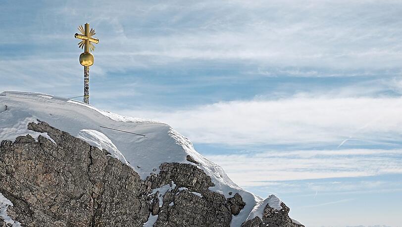 Das Gipfelkreuz auf der Zugspitze bekommt Gesellschaft, allerdings in sicherer Umgebung. Wer genau hinschaut, sieht, wie viele Sticker Besucher schon aufgeklebt haben.
