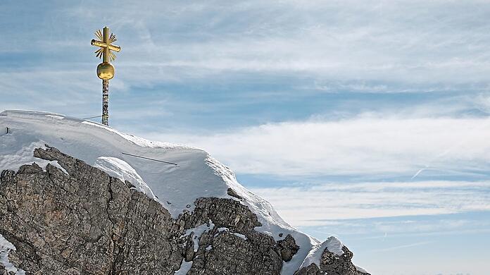 Das Gipfelkreuz auf der Zugspitze bekommt Gesellschaft, allerdings in sicherer Umgebung. Wer genau hinschaut, sieht, wie viele Sticker Besucher schon aufgeklebt haben.
