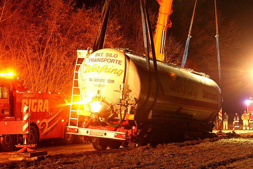 Ein Bergungsfahrzeug und zwei Kräne werden benötigt um den vollbeladenen LKW wieder auf die Straße zu ziehen.