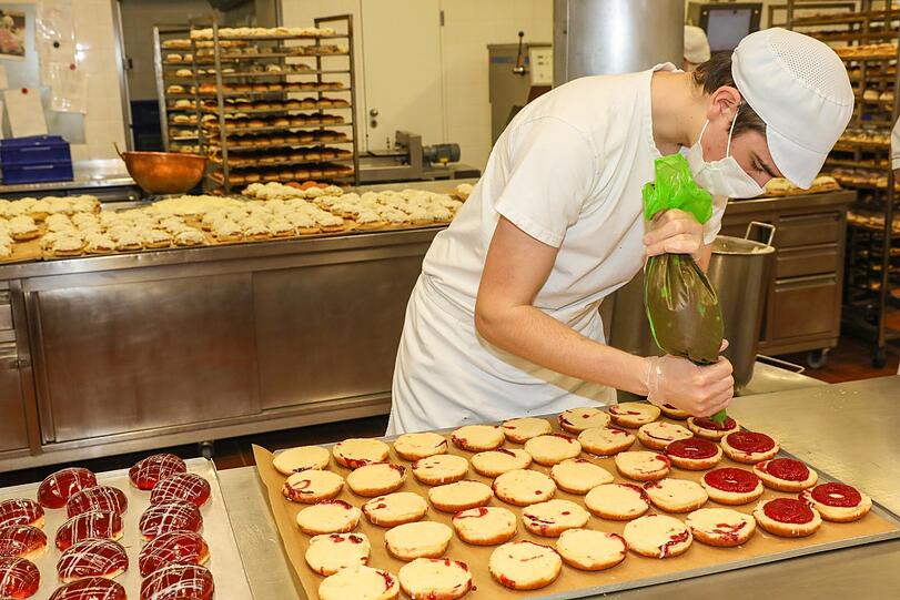 Tim Hauptmann konzentriert sich auf die Krapfenböden und versieht sie mit frischer Himbeermarmelade.