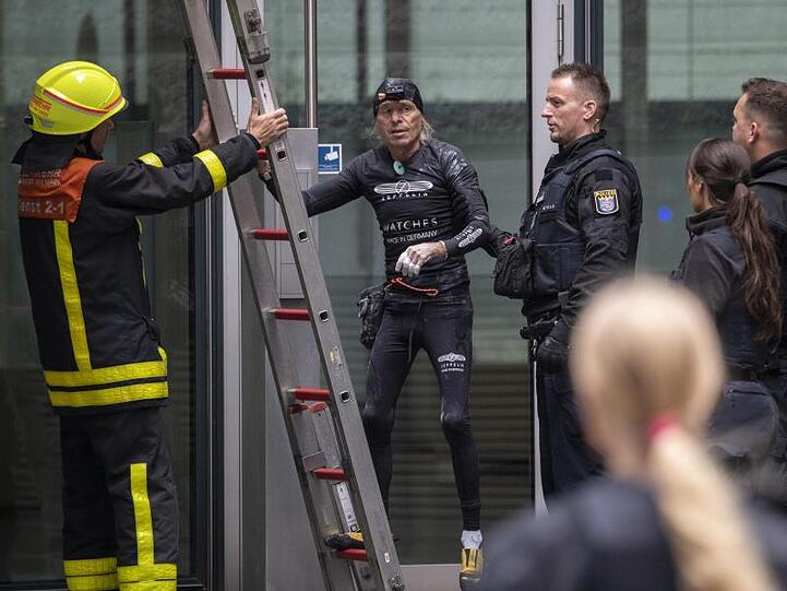 Nachdem er die Fassade des Skyper-Hochhauses wieder hinuntergeklettert war, wird der Extremkletterer von Polizisten in Empfang genommen.