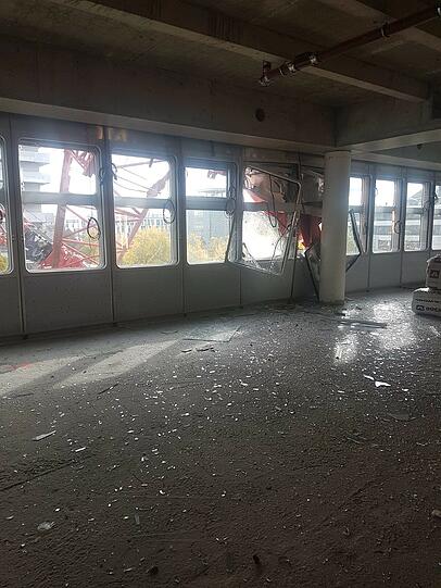 Glasscherben liegen im Innenraum des Gebäudes.  Außen kann man den umgestürzten Kran erkennen.