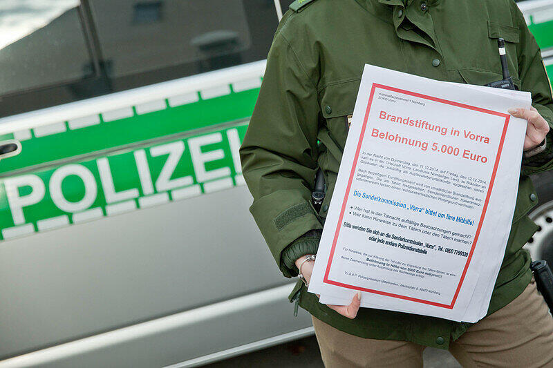 Eine Polizistin hält am 13.12.2014 in Vorra (Bayern) Fahndungszettel zum Brandanschlag in der Gemeinde in den Händen. Die Polizei sucht fieberhaft nach den Verbrechern.