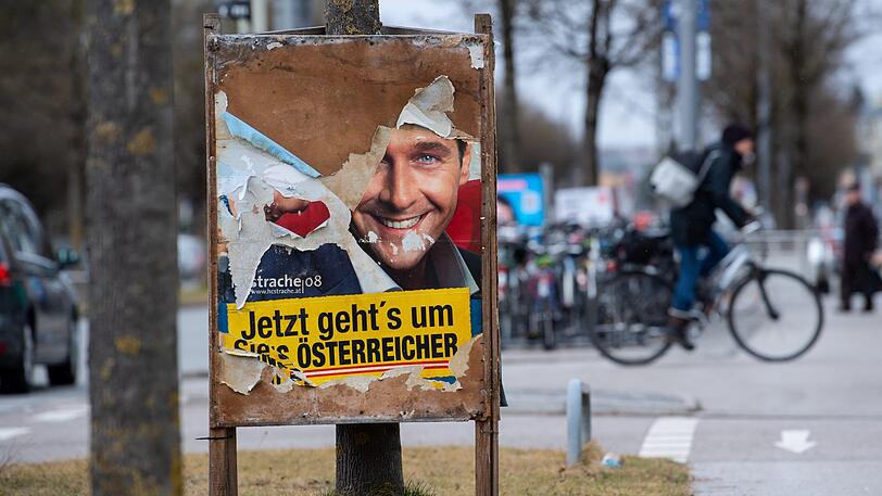 Ein zerstörtes Wahlplakat der CSU steht an einem Straßenrand. Unter dem abgerissenen Plakat kommt ein altes Wahlplakat von Heinz-Christian Strache (FPÖ) aus dem Jahr 2008 zum Vorschein.