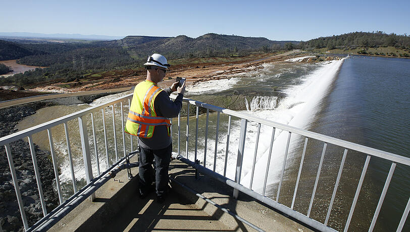 Jason Newton vom Department für Wasser-Reserven macht ein Foto vom Notüberlauf des Oroville-Staudamms in Oroville, Kalifornien (USA). Jason Newton vom Department für Wasser-Reserven macht ein Foto vom Notüberlauf des Oroville-Staudamms in Oroville, Kalifornien (USA).