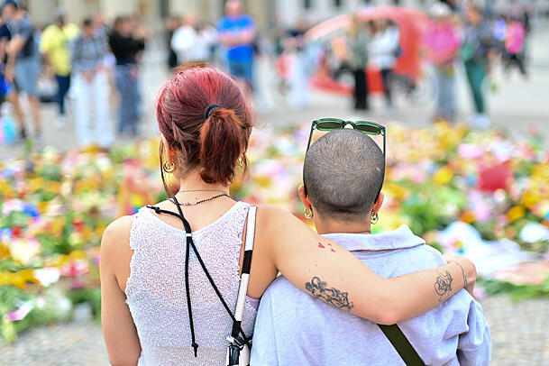 Menschen schauen sich Beileidsbekundungen, Blumen, Flaggen und Kerzen an, die vor dem Brandenburger Tor abgelegt wurden.
