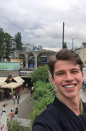 Moritz Tostmann, Praktikant: "Ich, ich, ich fotografiere mich. So ein bisschen Selbstdarstellung gehört ja schon zum Selfie. Angebracht ist das aber durchaus, wenn man sagen möchte: An diesem Ort war ich und der ist ziemlich kurios. So wie die Münchner Freiheit: An den großen Schachfeldern liefern sich angetrunkene Rentner stundenlange Duelle, der 24-Stunden-Kiosk rettet so manchem Nikotinsüchtigen den Tag und zahlreiche Passanten versuchen, mit Kaffeebecher und Semmel die Tram zu erwischen.
Nein, es handelt sich um keinen Umschlagsplatz für Rauschmittel, sondern um einen Ort, an dem die Hektik Tagesordnung ist. Und die muss kompensiert werden. Donnerstags sorgt der Markt dafür, dass auch alle ,Gourmet-Süchtigen&rsquo; auf ihre Kosten kommen."