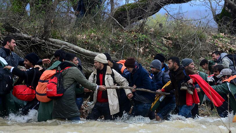 Migranten und freiwillige Helfer bilden eine Menschenkette im Fluss. Migranten und freiwillige Helfer bilden eine Menschenkette im Fluss.