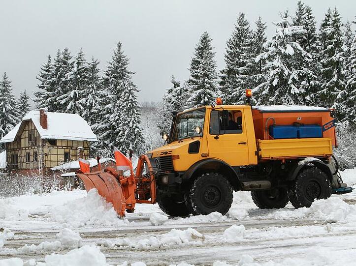 Ein Räumfahrzeug befreit einen Parkplatz vom Schnee