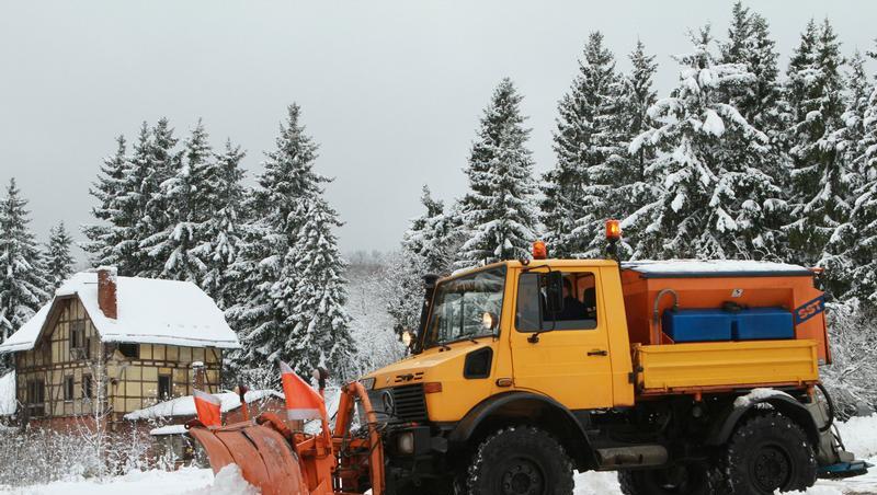 Ein Räumfahrzeug befreit einen Parkplatz vom Schnee Ein Räumfahrzeug befreit einen Parkplatz vom Schnee