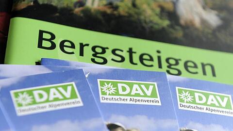 Prospekte mit dem Logo des Deutschen Alpenvereins (DAV) liegen auf einem Tisch. Foto: picture alliance / dpa/Illustration