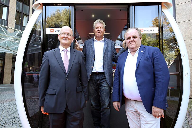 Vor einer Gondel: Maurer-Chef Christian Braun, Oberbürgermeister Dieter Reiter und Riesenrad-Spezialist Ronald Bussink.
