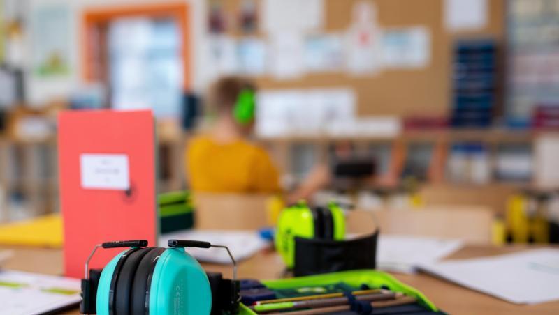 Ein Mäppchen und ein Gehörschutz liegen im Klassenzimmer einer Grundschule auf einem Tisch. (Archivbild) Ein Mäppchen und ein Gehörschutz liegen im Klassenzimmer einer Grundschule auf einem Tisch. (Archivbild)