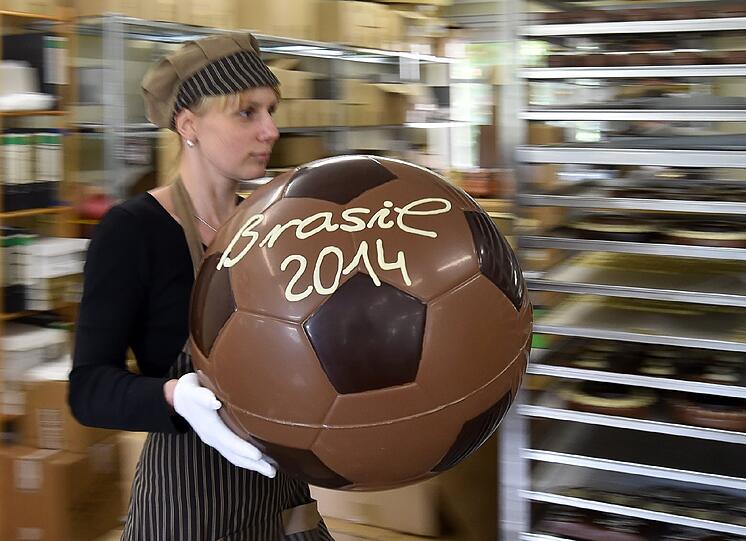 Einen großen Schokoladenfußball mit der Aufschrift "Brasil 2014" trägt Katja Schumann von der Confiserie Felicitas GmbH in Hornow (Brandenburg). Die Produktion von Fußbällen, Spielern und Pokalen aus reiner Kakaobutter läuft hier derzeit auf Hochtouren.