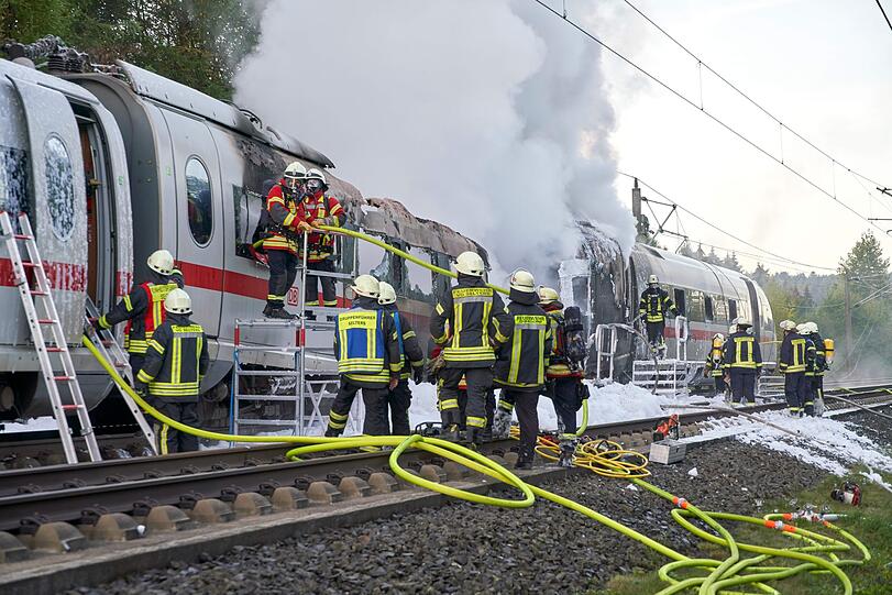 Feuerwehrleute löschen den brennenden ICE-Wagen, der auf der Schnellstrecke zwischen Frankfurt und Köln Feuer gefangen hatte.