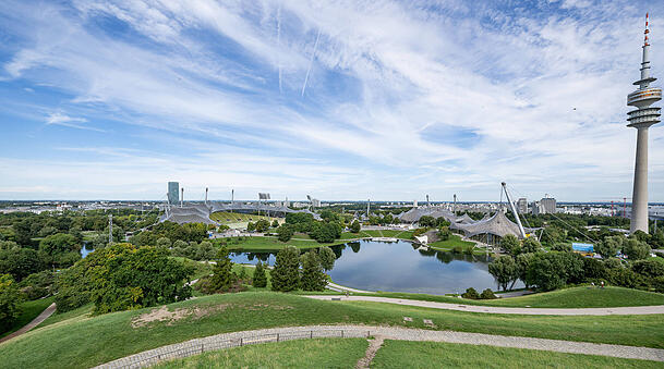 Der Olympiapark heute mit Turm, See und  Schwimmhalle.