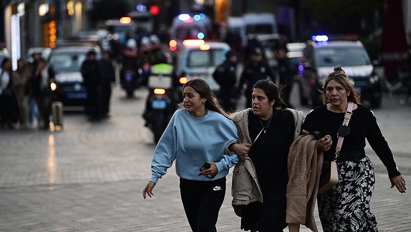 Drei Frauen flüchten vom Ort der Explosion, während Polizisten die Gegend absperren.