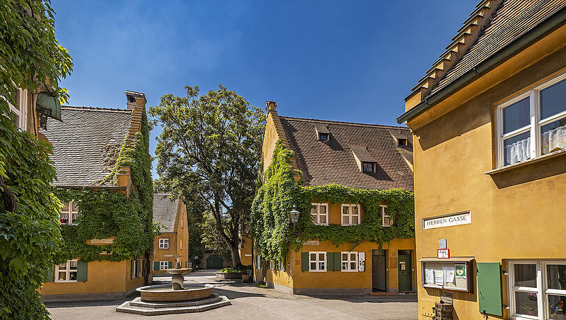 Idylle mitten in der Großstadt Augsburg: Ockerfarbige Häuser bestimmen das Bild der Fuggerei, deren Zentrum ein schlichter Brunnen bildet.