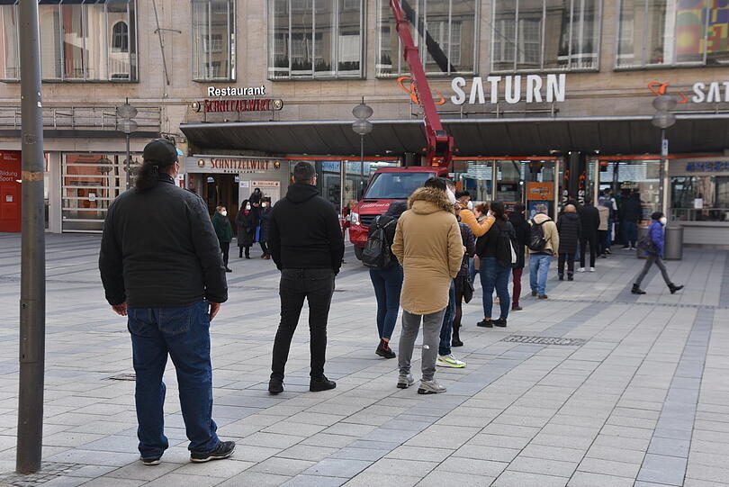 Kunden stehen vor der "Saturn"-Filiale in der Fußgängerzone an.