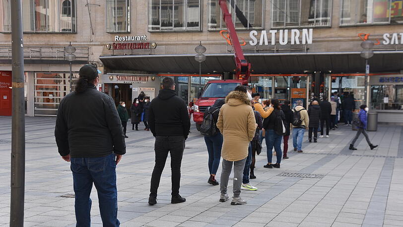 Kunden stehen vor der "Saturn"-Filiale in der Fußgängerzone an. Kunden stehen vor der "Saturn"-Filiale in der Fußgängerzone an.