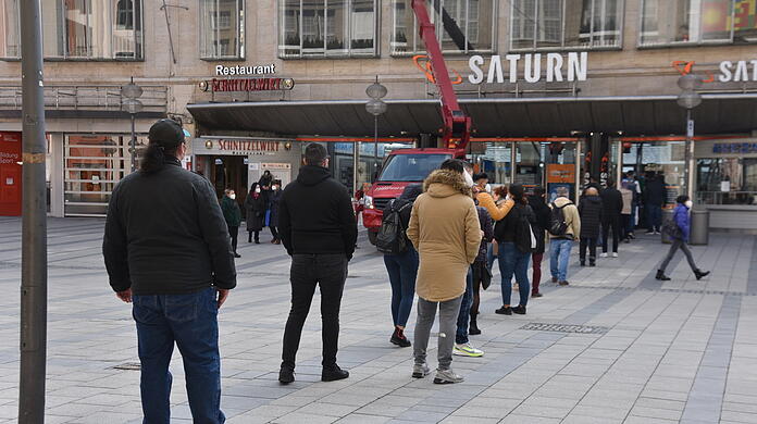 Kunden stehen vor der "Saturn"-Filiale in der Fußgängerzone an.