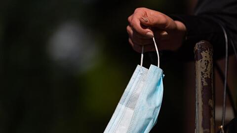 Ein Frau hält ihren Mundschutz in der Hand.