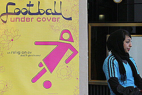 Narmila Fathi steht in Berlin neben einem Plakat zu dem Kinofilm "Football Under Cover", in dem die Iranerin mitgewirkt hat.