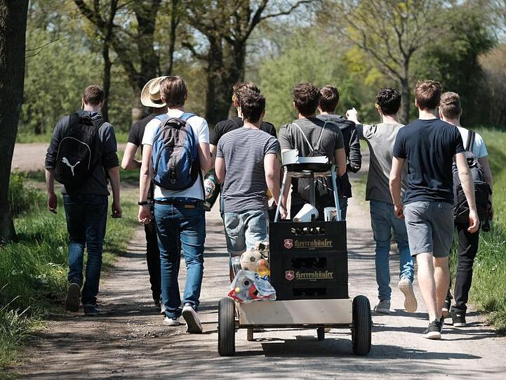 Eine Gruppe junger Männer feiert den Vatertag mit einem mit Bier gefüllten Bollerwagen.