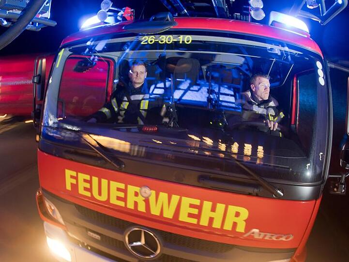 Feuerwehrleute sitzen für Fotoaufnahmen in einem Leiterwagen (Aufnahme mit langer Verschlusszeit). Foto: Julian Stratenschulte/Archiv