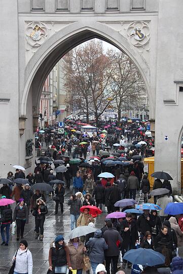 Getümmel im Schneeregen: Menschenmengen mit Regenschirmen schieben sich am Stachus in die Fußgängerzone.