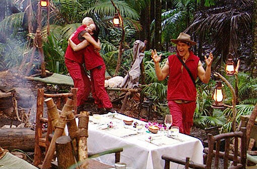 Als die drei Finalisten (v.li.) Brigitte Nielsen, Kim Debkowski und Rocco Stark gemeinsam vom Dschungeltelefon zurück ins Camp kommen, steht ein schön gedeckter Tisch mit Tischdecke, Servietten, Kerzen und Blumendeko mitten im Camp.