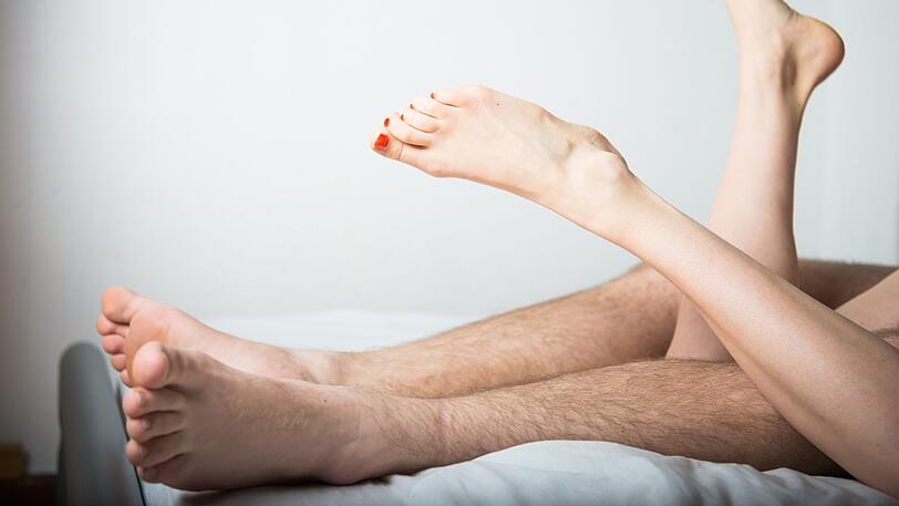 Ein junges Paar liegt im Bett. (Symbolbild)