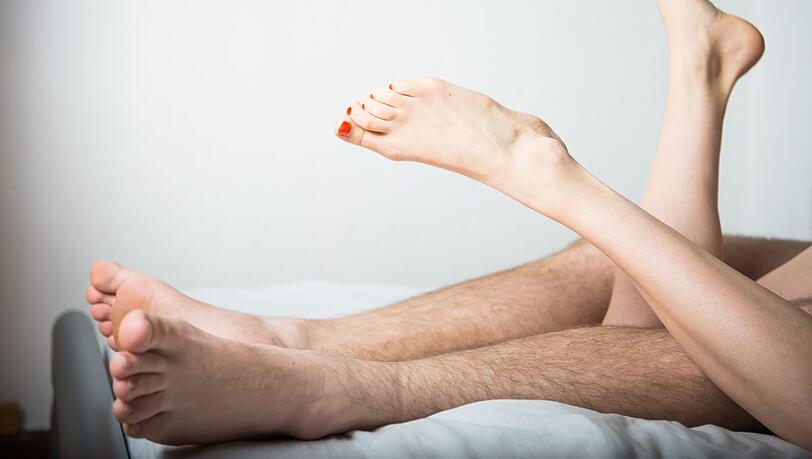 Ein junges Paar liegt im Bett. (Symbolbild)