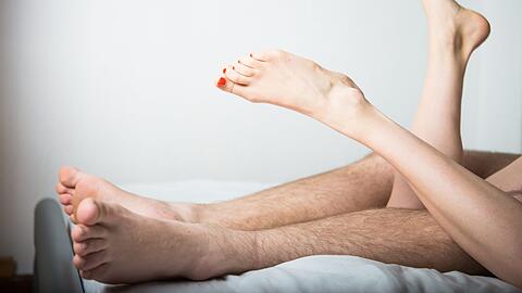Ein junges Paar liegt im Bett. (Symbolbild)
