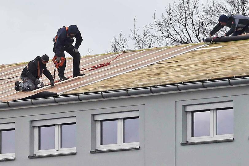 Dachdecker flicken ein beschädigtes Dach in der Steinerstraße.